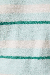 Close-up of a fabric with green and white stripes on a light blue background