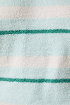 Close-up of a fabric with green and white stripes on a light blue background