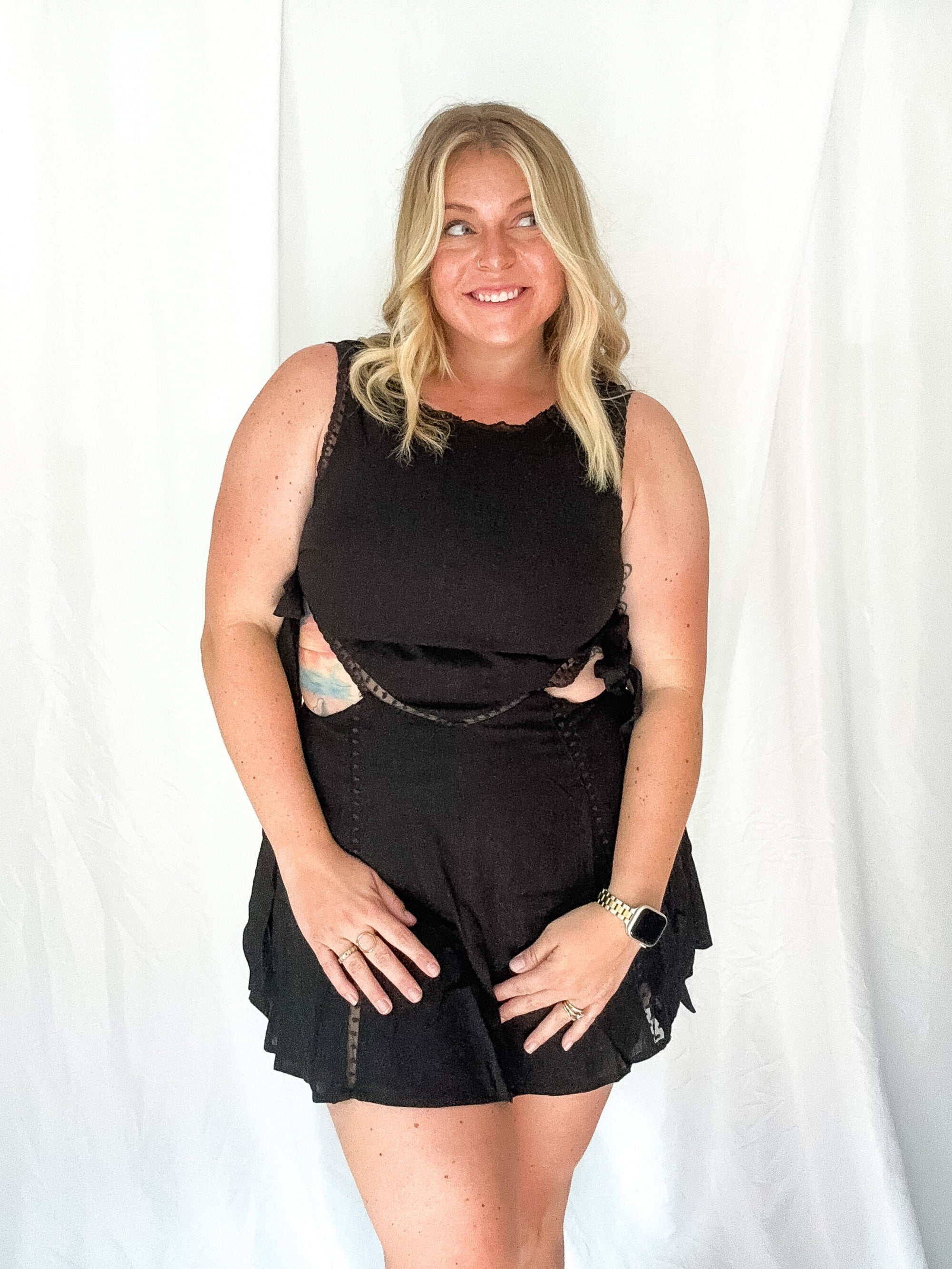 Woman wearing a black sleeveless top and shorts against a white background