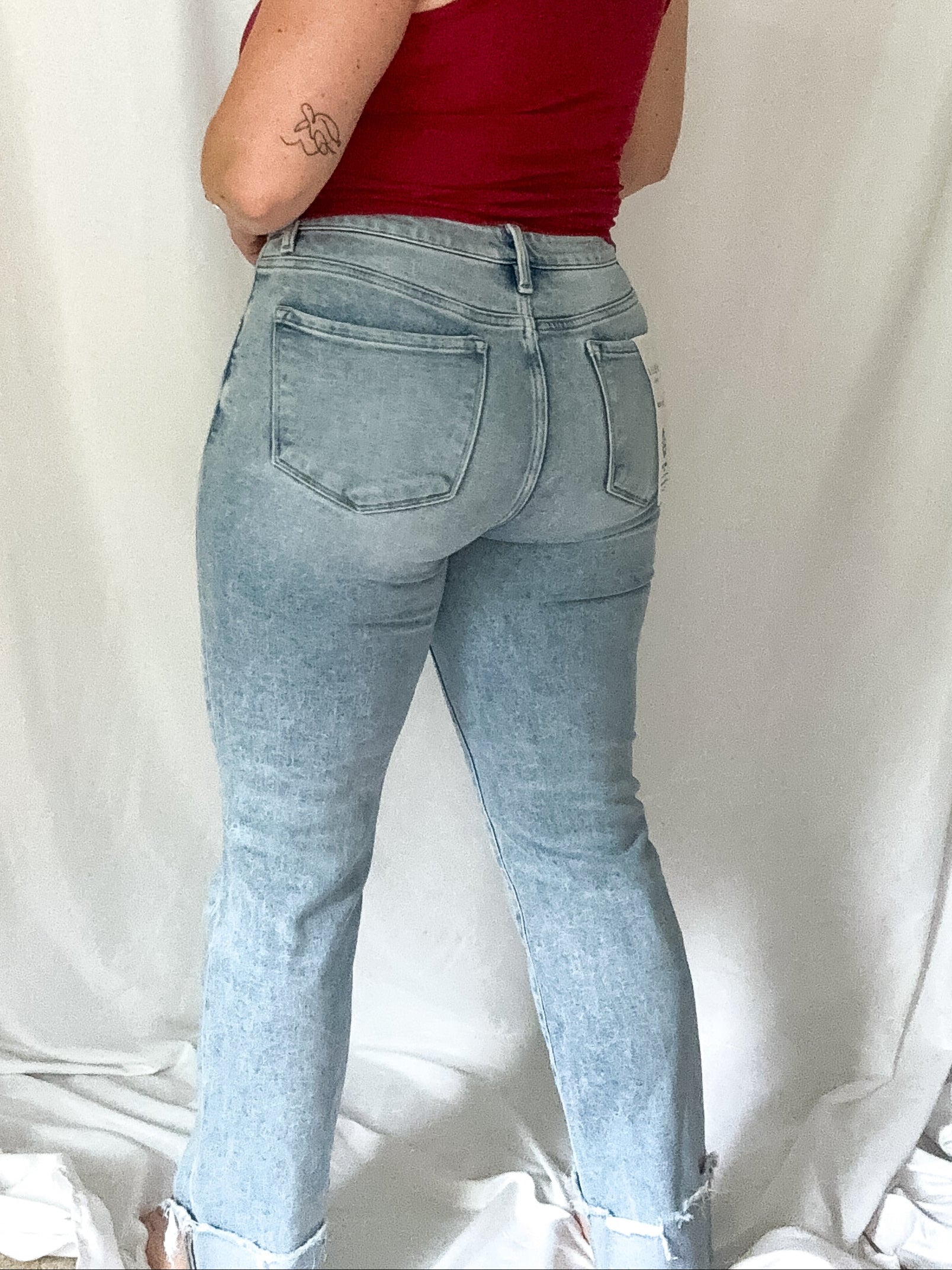 Woman wearing a red top and light blue jeans against a white background