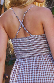 Woman in a checkered dress standing in a garden setting