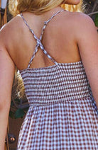 Woman in a checkered dress standing in a garden setting