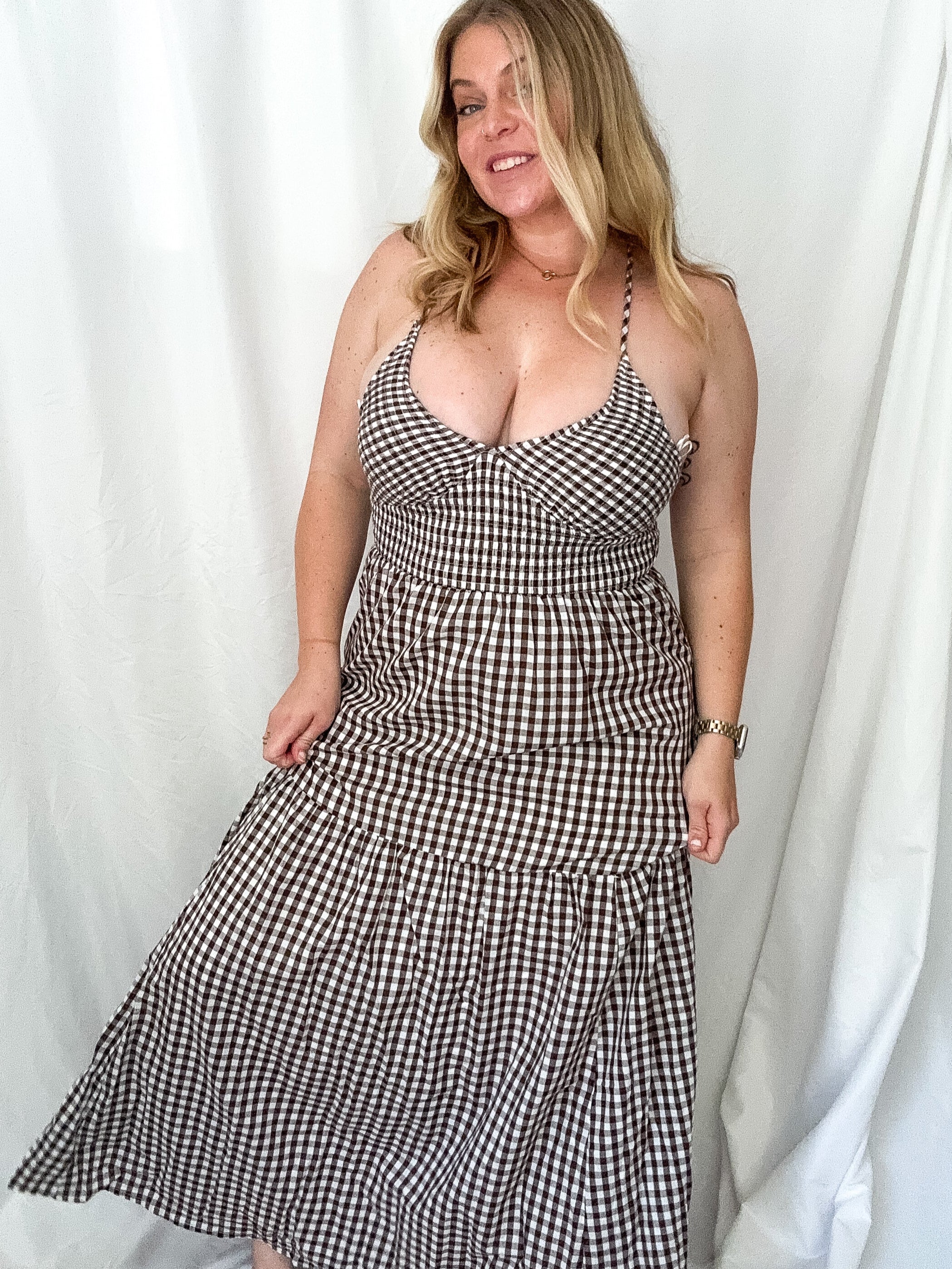 Woman wearing a black and white checkered dress against a white curtain background