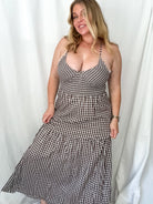 Woman wearing a black and white checkered dress against a white curtain background