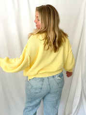 Person wearing a yellow sweater and light blue jeans against a white background