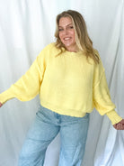 Person wearing a yellow sweater and blue jeans against a white background
