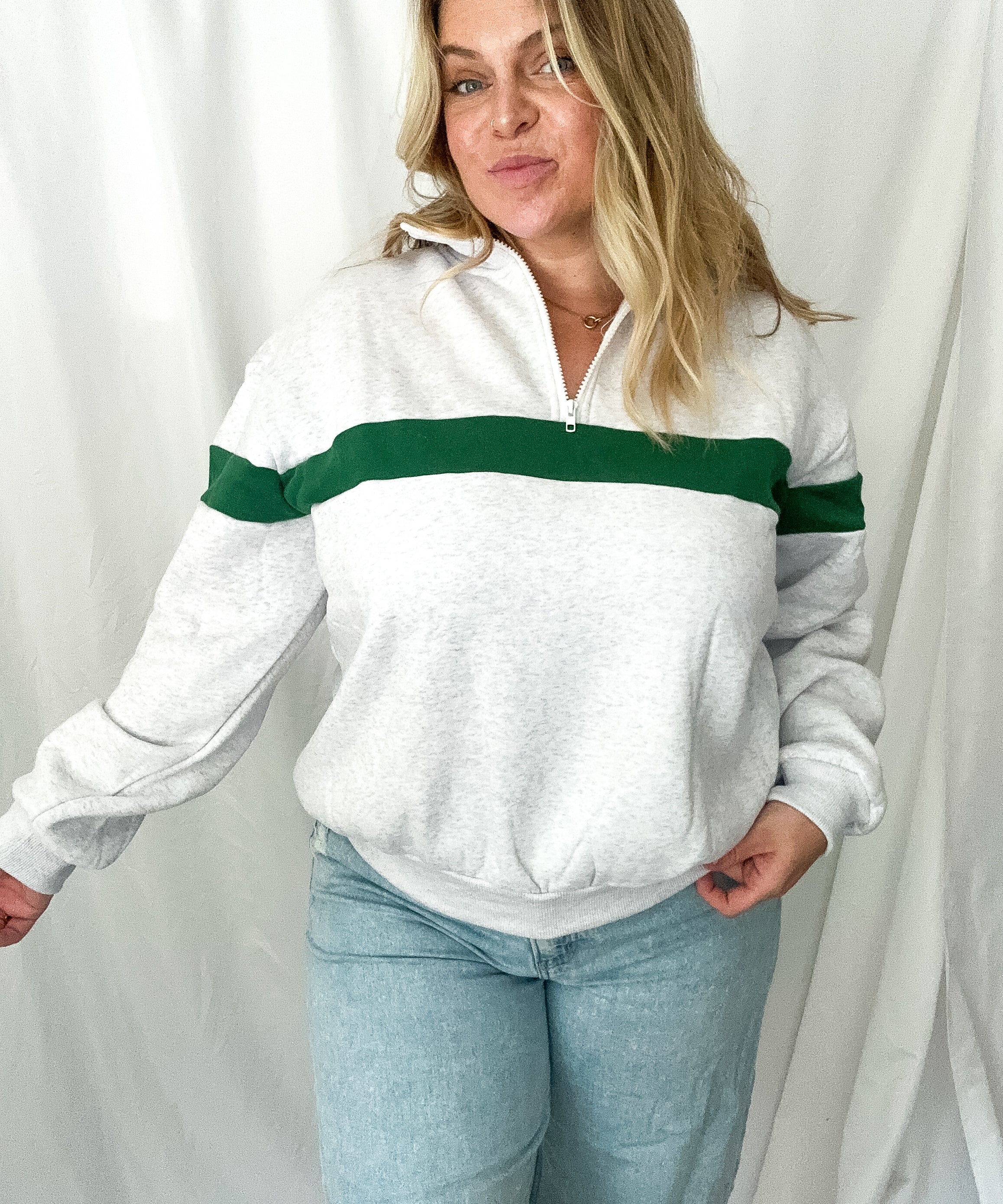 Woman wearing a white sweater with green stripes against a white background