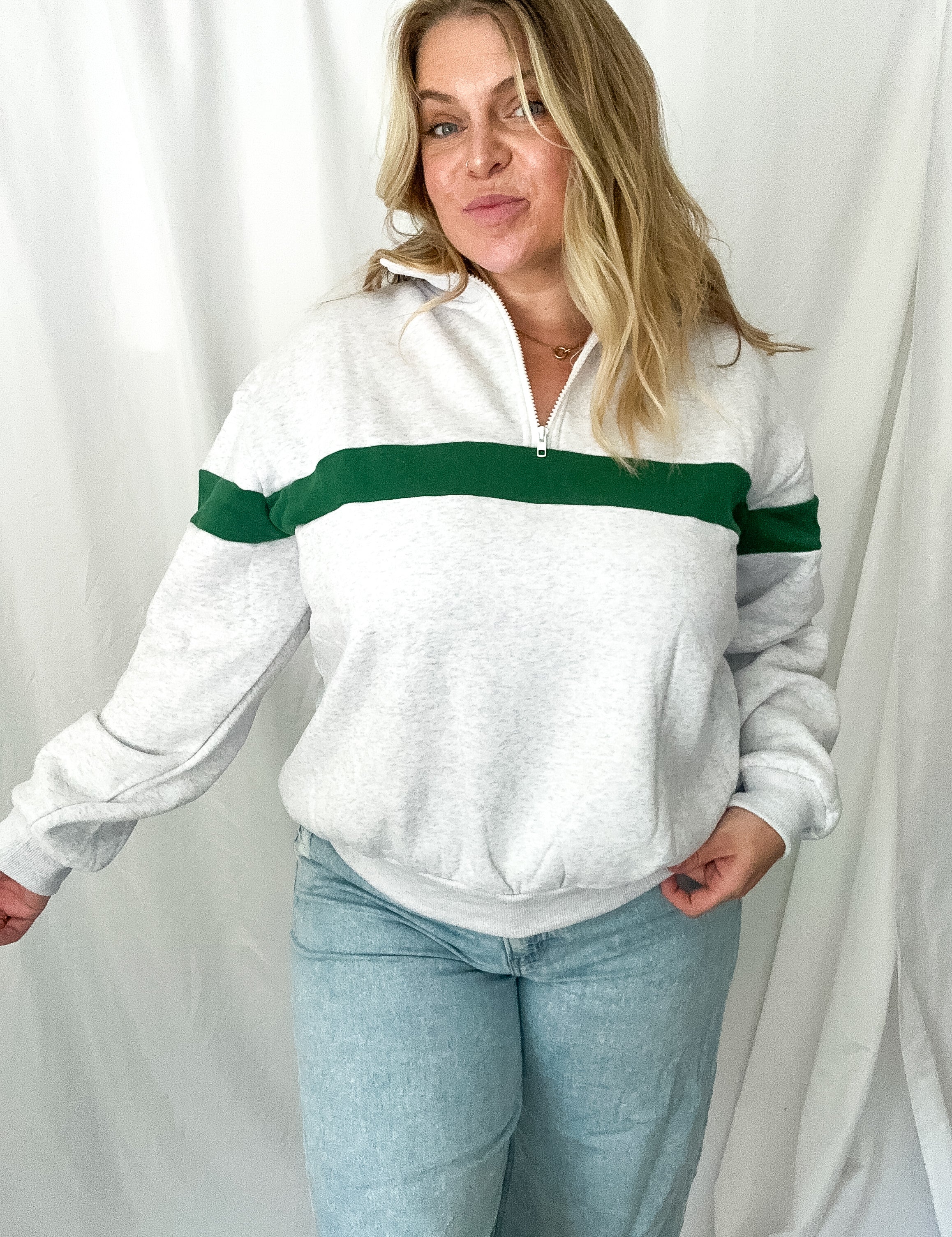Woman wearing a white sweater with green stripes against a white background