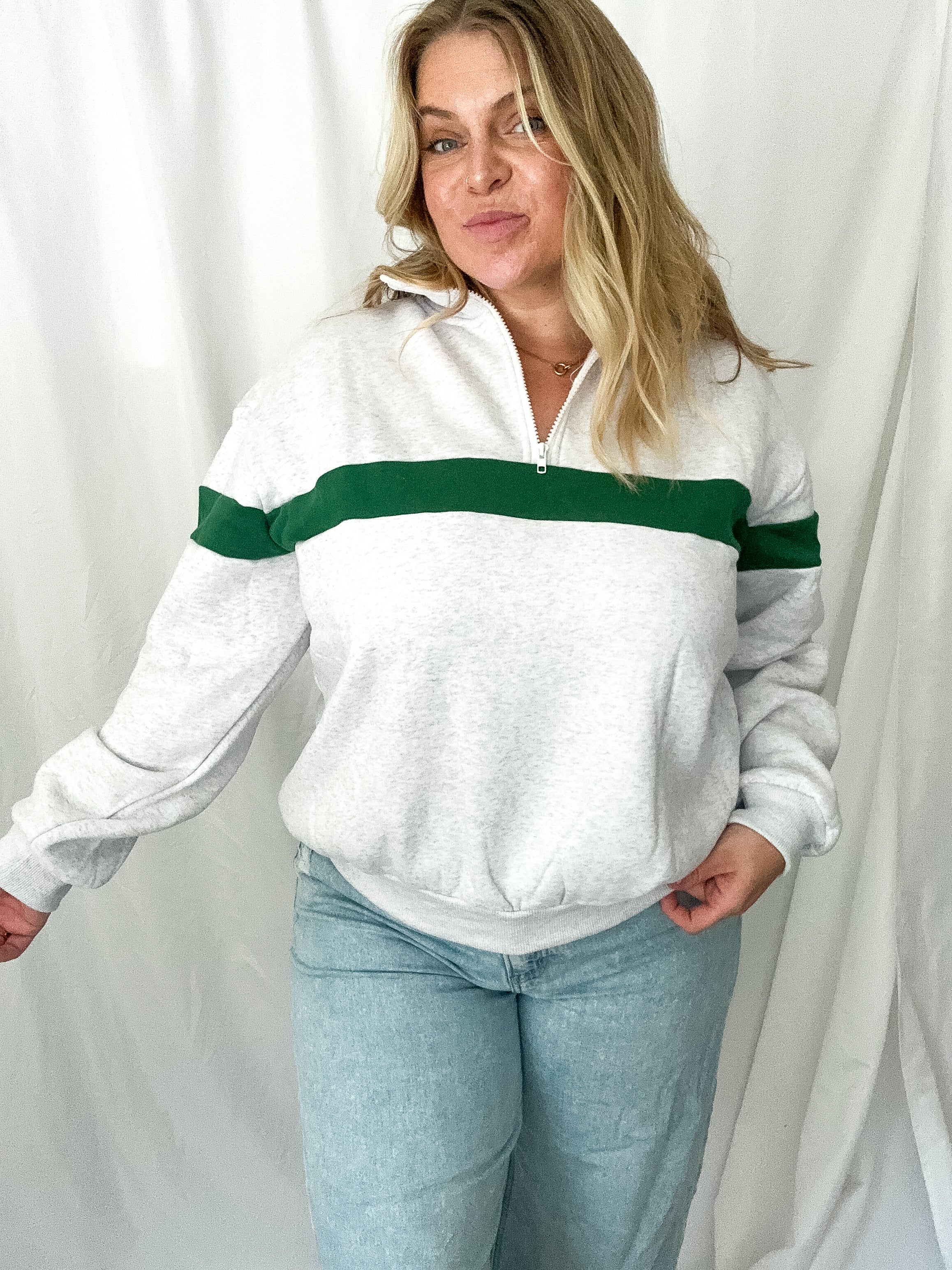 Woman wearing a white sweater with green stripes against a white background
