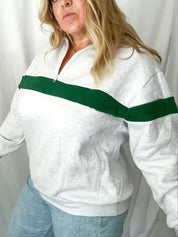 Woman wearing a white sweatshirt with a green stripe against a plain background