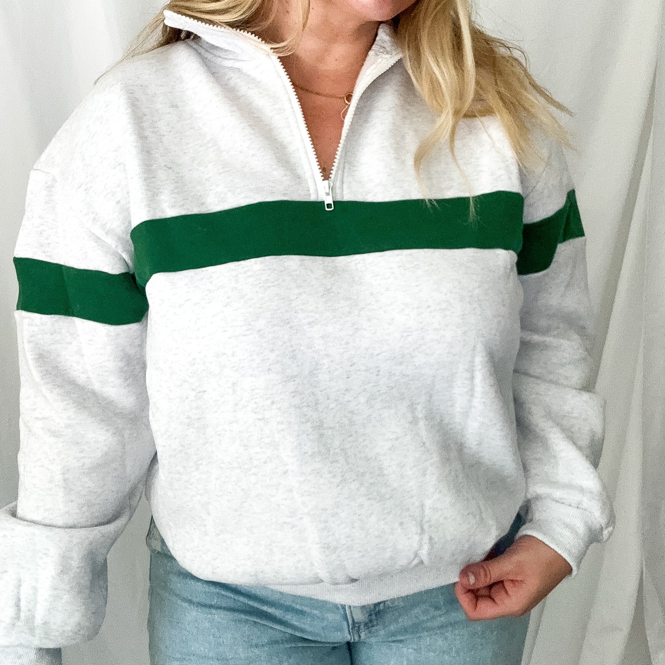 Person wearing a white sweater with green stripes against a plain background