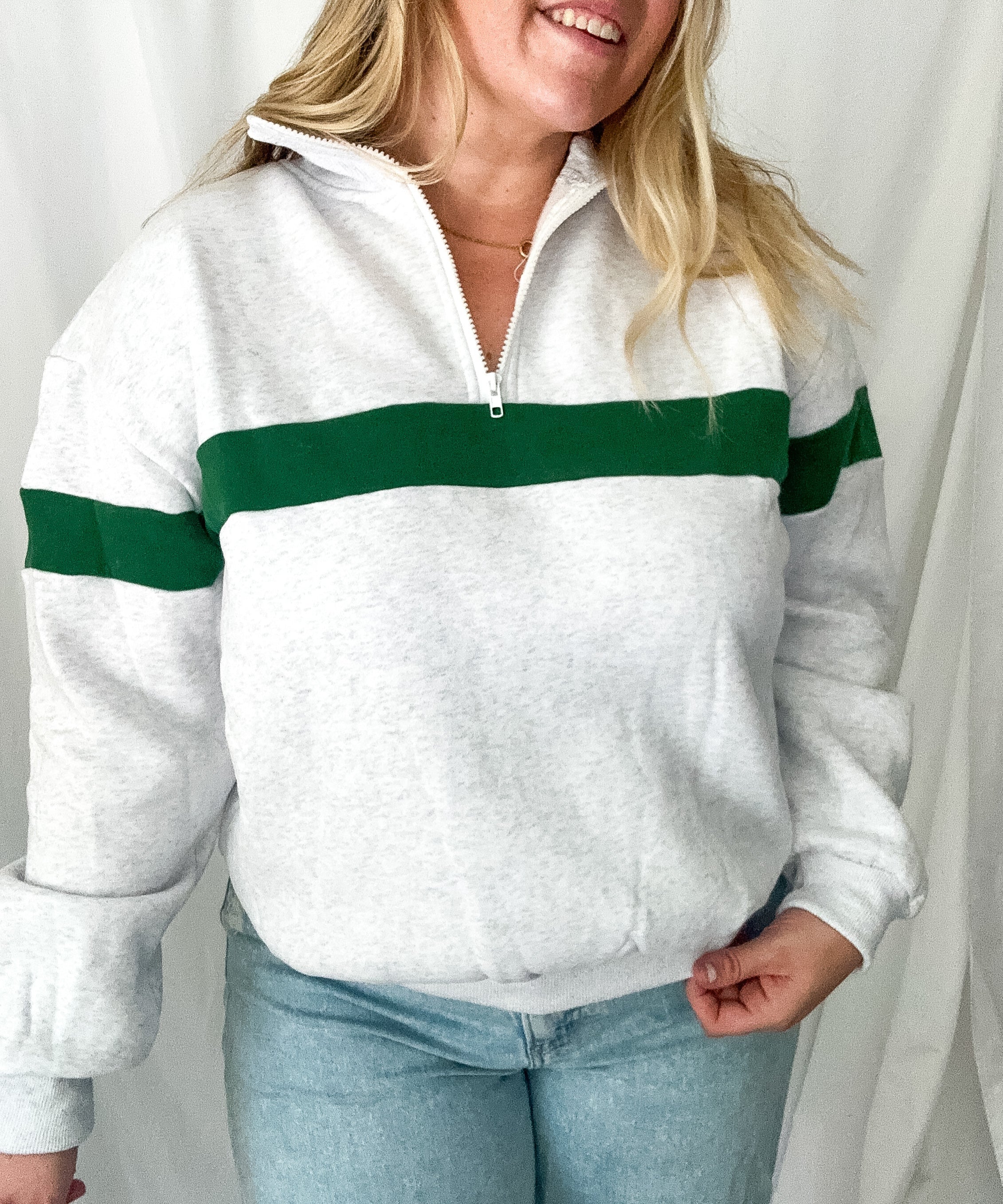 Person wearing a white sweater with green stripes against a plain background