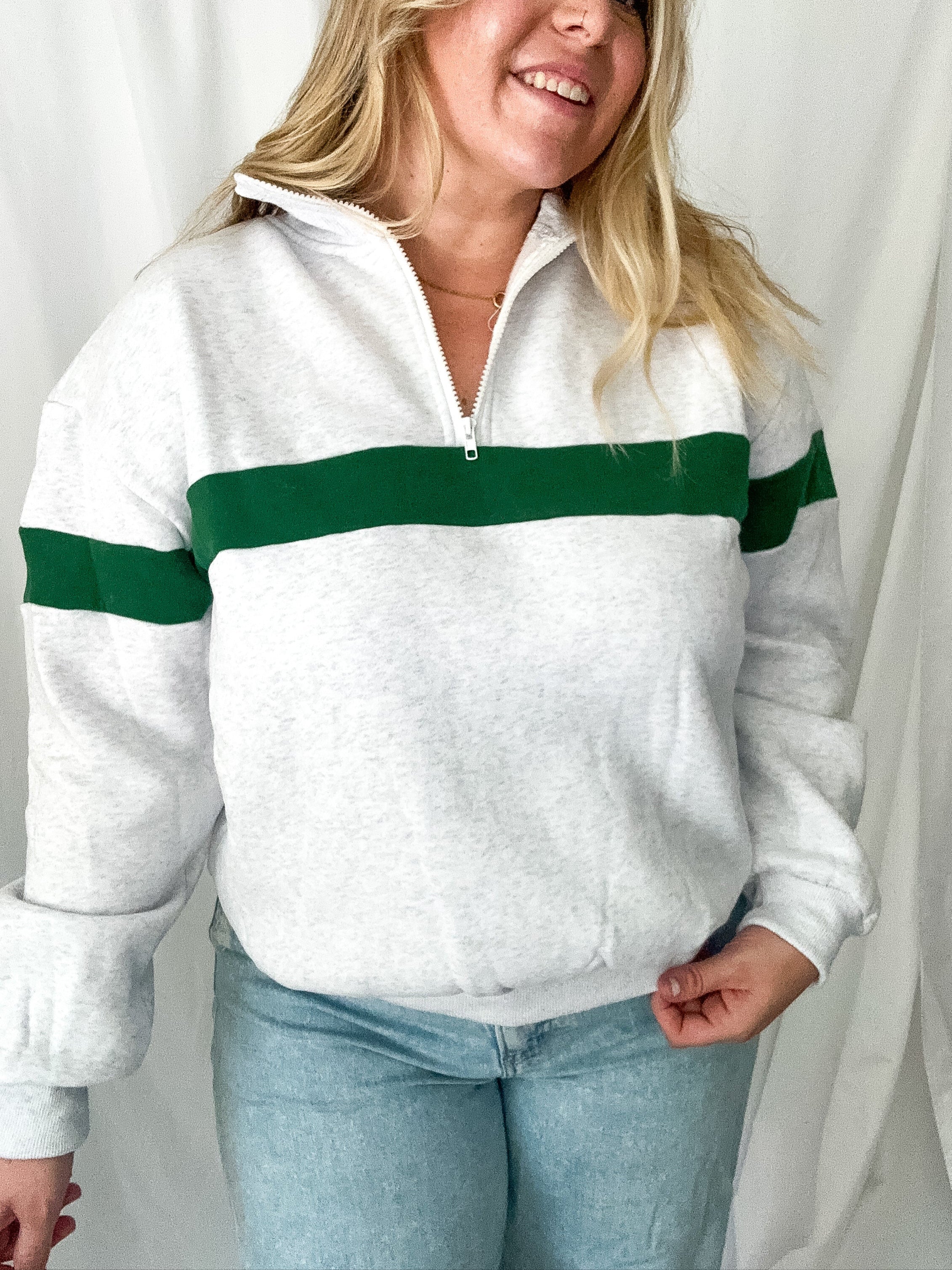 Person wearing a white sweater with green stripes against a plain background