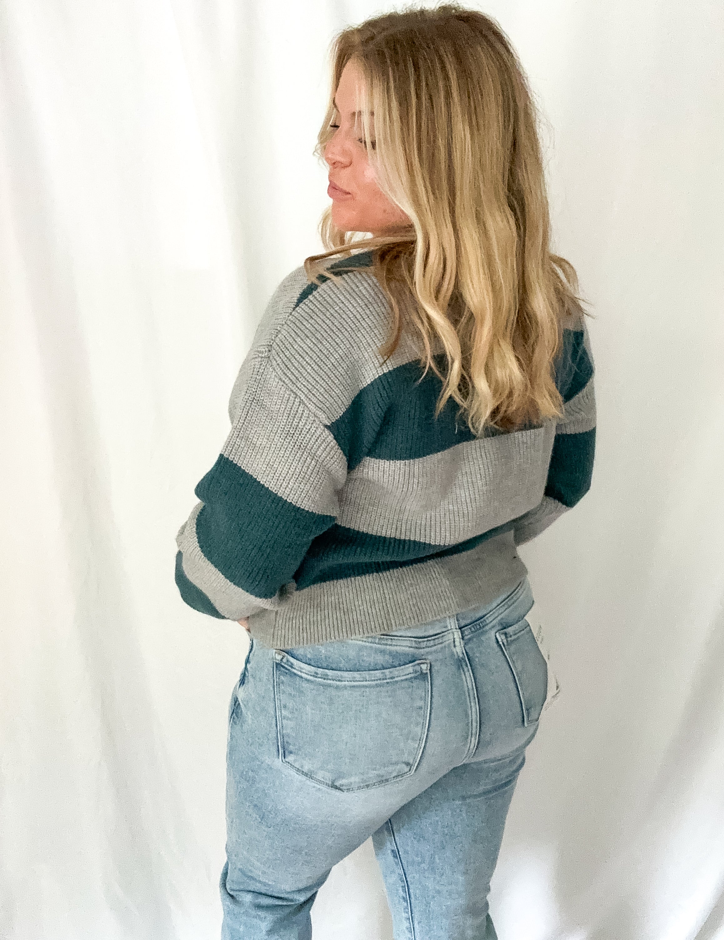 Person wearing a striped sweater and jeans against a white background