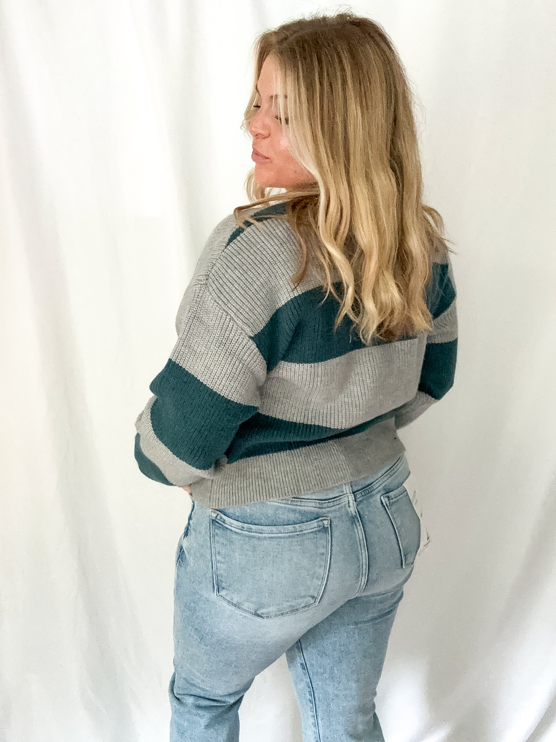 Person wearing a striped sweater and jeans against a white background