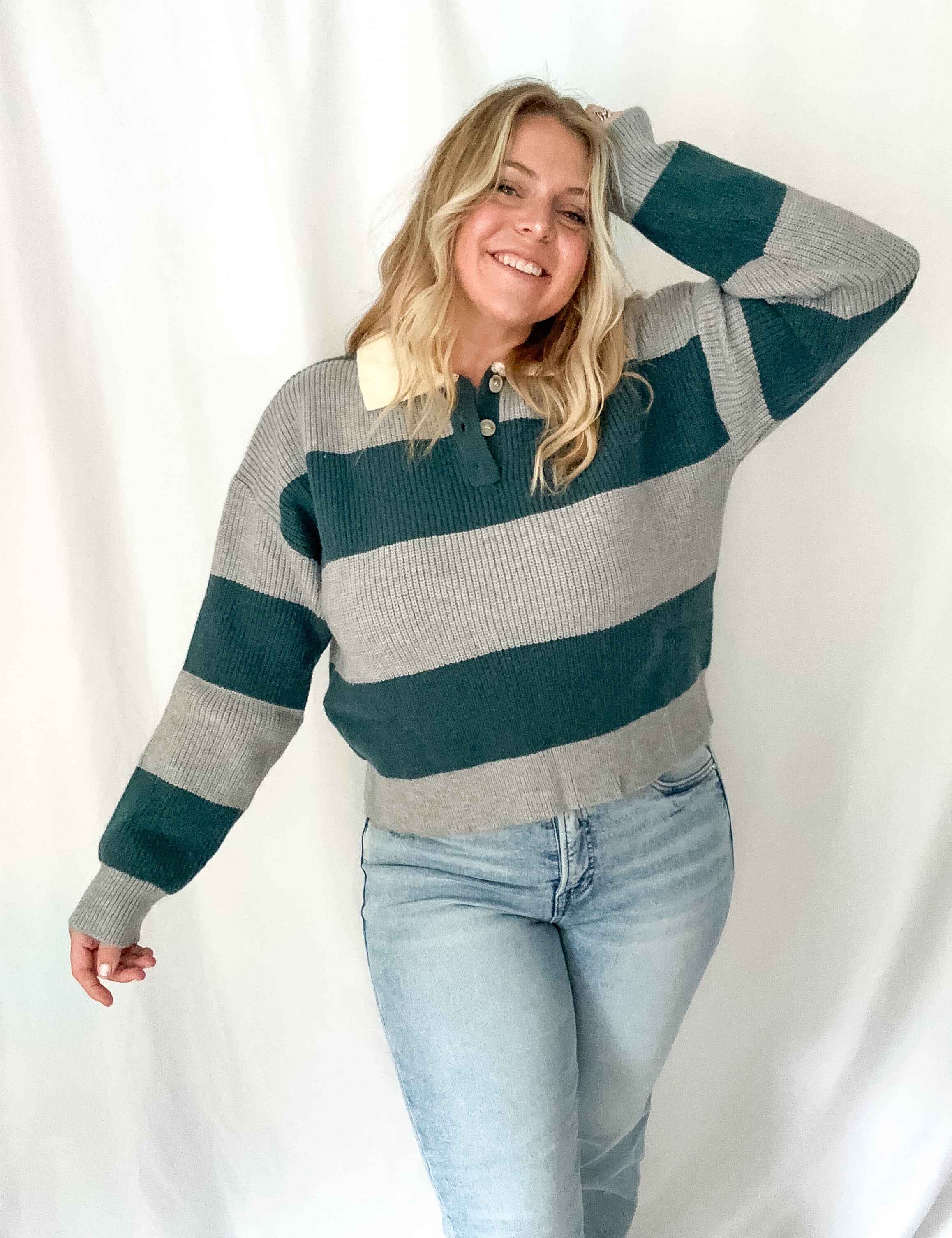 Woman wearing a striped sweater and jeans against a white background