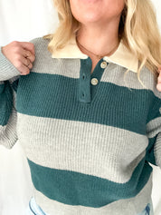 Person wearing a striped sweater with green, gray, and beige colors.