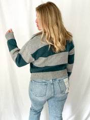 Person wearing a striped sweater and jeans against a white background