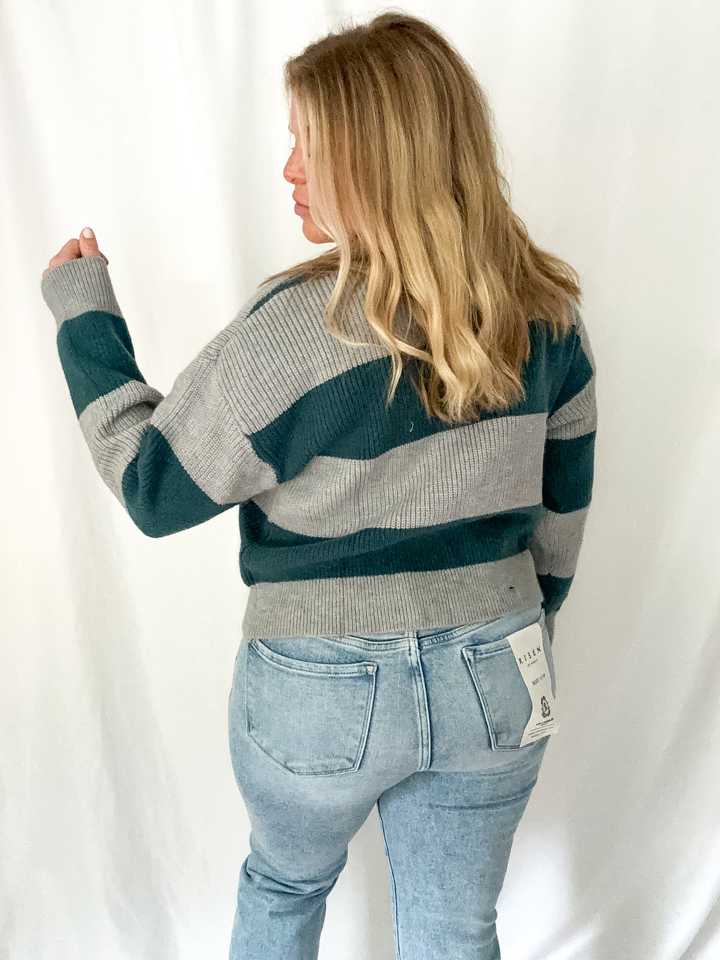 Person wearing a striped sweater and jeans against a white background