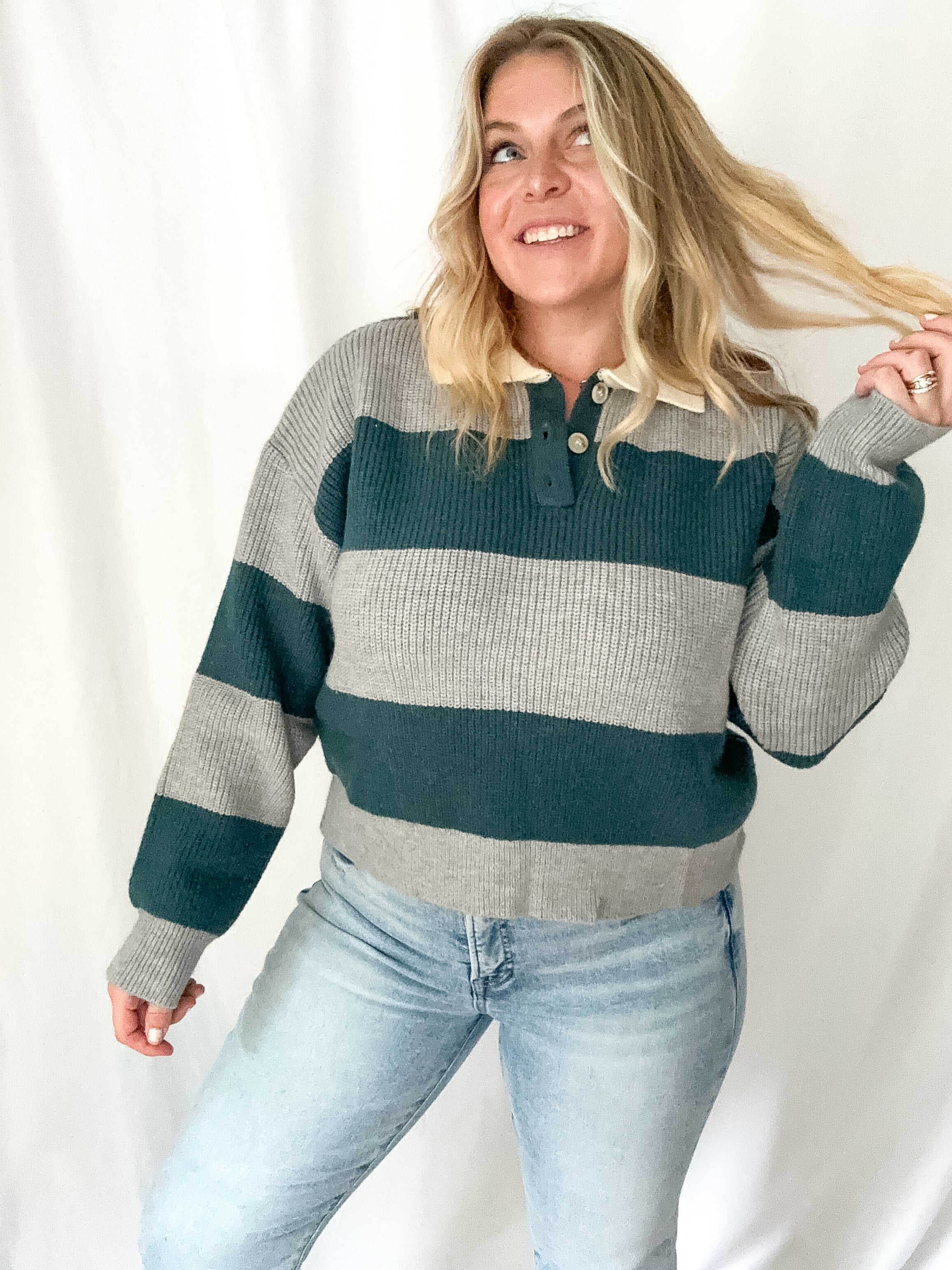 Woman wearing a striped sweater and jeans against a white background
