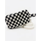 Checkered cosmetic bag in black and white with a handle and zipper closure.